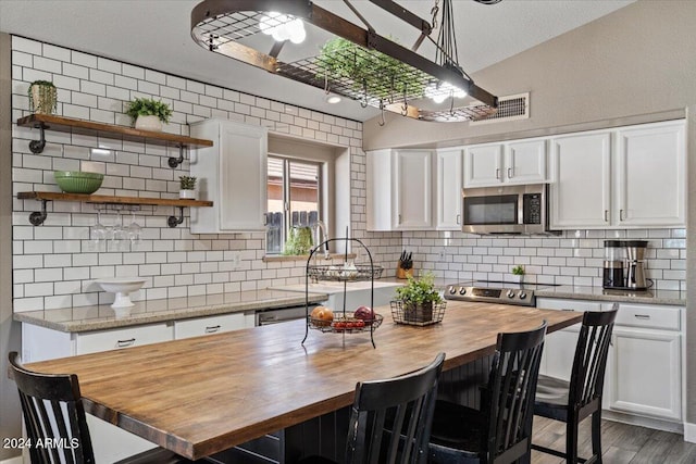 kitchen with white cabinets, dark hardwood / wood-style flooring, appliances with stainless steel finishes, and wooden counters