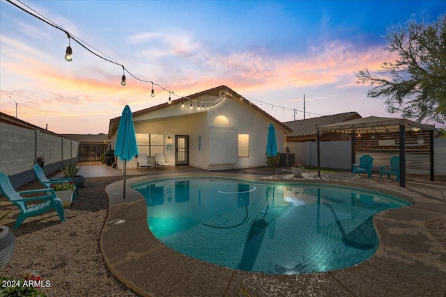 pool at dusk with central AC and a patio area