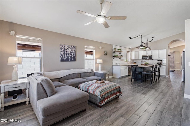 living room featuring dark hardwood / wood-style flooring, vaulted ceiling, and ceiling fan