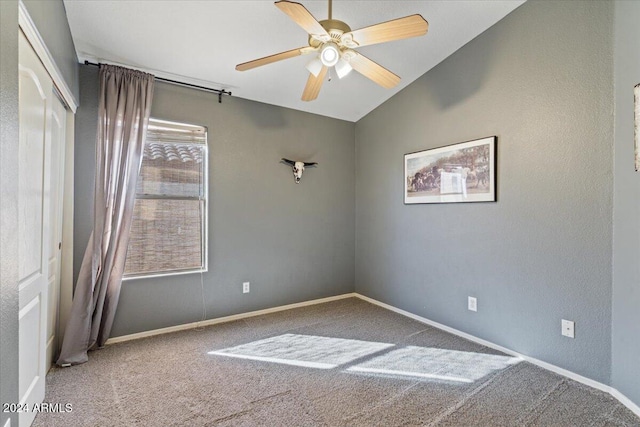 carpeted spare room with ceiling fan and vaulted ceiling