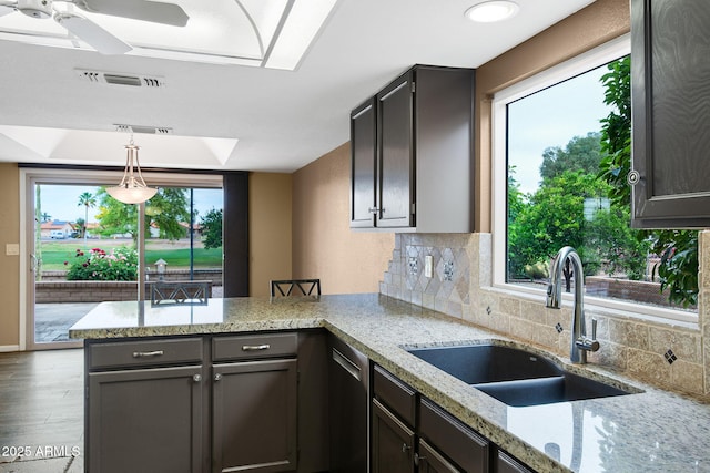 2461 Leisure World, Mesa, AZ 85206 - kitchen with visible vents, a sink, a peninsula, wood finished floors, and backsplash