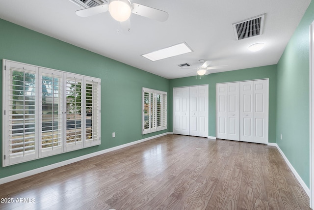 2461 Leisure World, Mesa, AZ 85206 - unfurnished bedroom with two closets, wood finished floors, visible vents, and a skylight