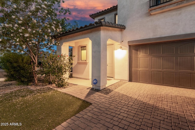 11541 E Corbin Ave, Mesa, AZ 85212 - exterior entry at dusk with a garage, decorative driveway, stucco siding, and a tile roof