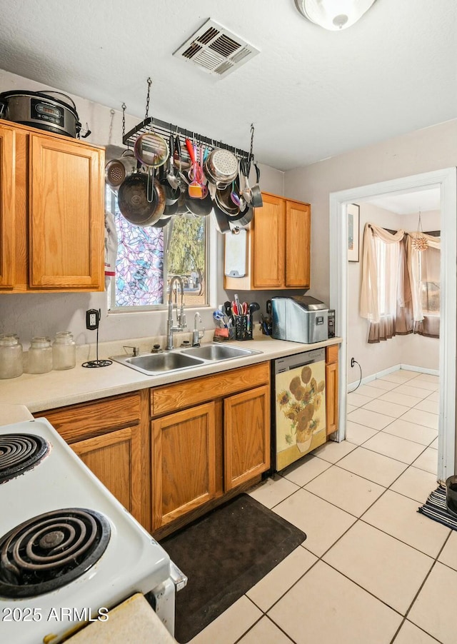 kitchen with light tile patterned floors, a sink, visible vents, light countertops, and dishwasher