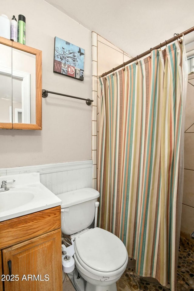 full bath with a wainscoted wall, toilet, a shower stall, and vanity