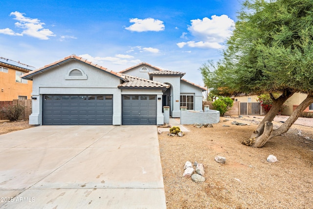 mediterranean / spanish-style house featuring fence, driveway, an attached garage, stucco siding, and a tile roof