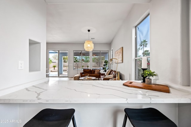 kitchen featuring hanging light fixtures, light stone countertops, and a breakfast bar