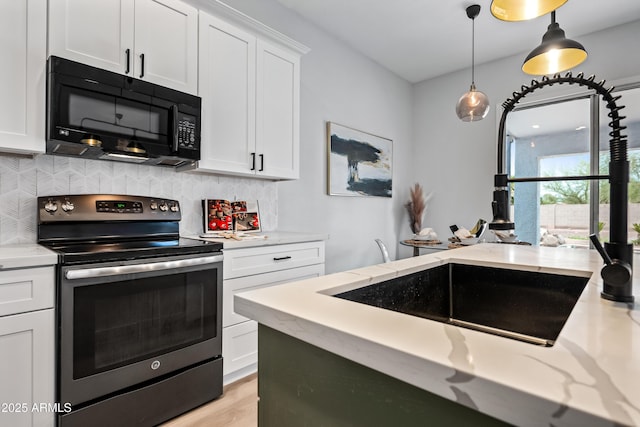 kitchen featuring black microwave, pendant lighting, stainless steel electric range oven, decorative backsplash, and white cabinetry