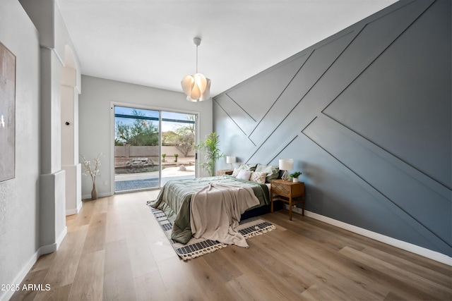 bedroom with wood finished floors, baseboards, and access to outside