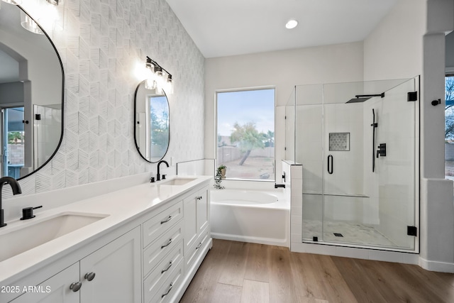 full bath featuring a sink, a garden tub, wood finished floors, and a shower stall