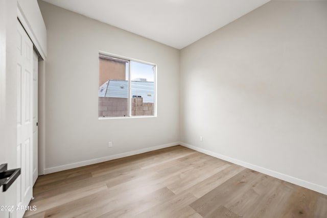 unfurnished bedroom with baseboards, light wood-type flooring, and a closet