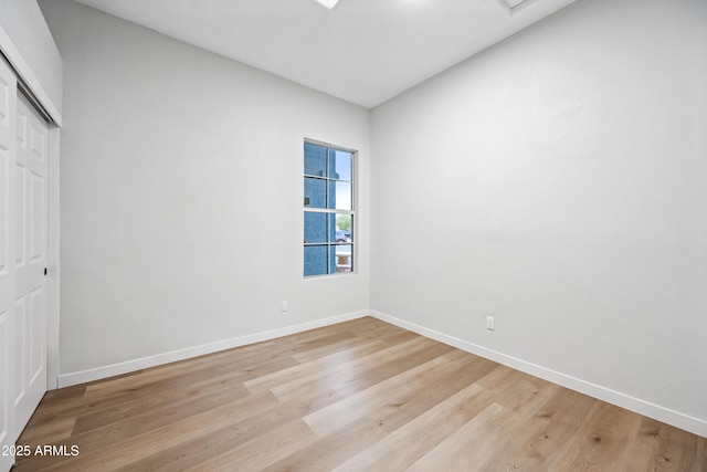 unfurnished bedroom with a closet, baseboards, and light wood finished floors