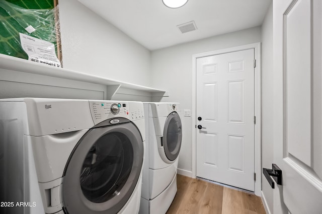 laundry room featuring light wood-type flooring, visible vents, washing machine and dryer, baseboards, and laundry area