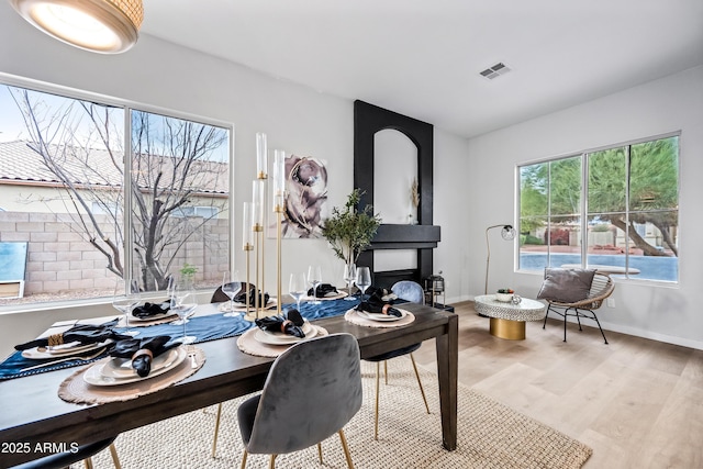 dining space with light wood finished floors, visible vents, and baseboards