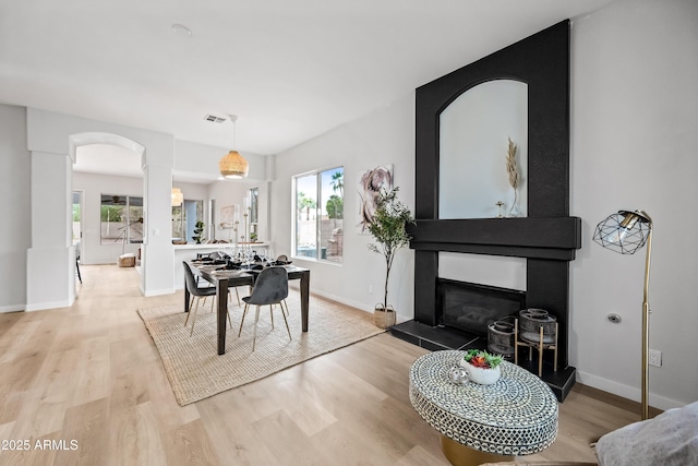 dining room featuring wood finished floors, visible vents, ornate columns, baseboards, and arched walkways