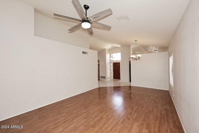 empty room with wood-type flooring, ceiling fan with notable chandelier, and vaulted ceiling