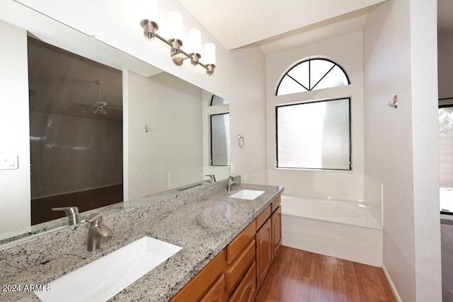 bathroom featuring hardwood / wood-style floors, vanity, ceiling fan, and a bathing tub