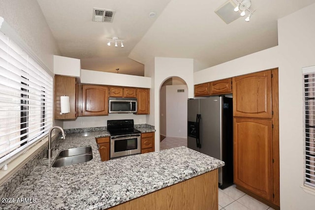 kitchen featuring light stone countertops, stainless steel appliances, vaulted ceiling, sink, and light tile patterned flooring