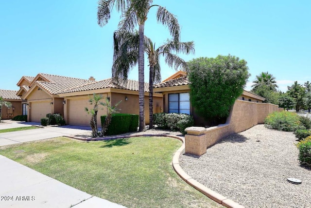 mediterranean / spanish home featuring a front yard and a garage