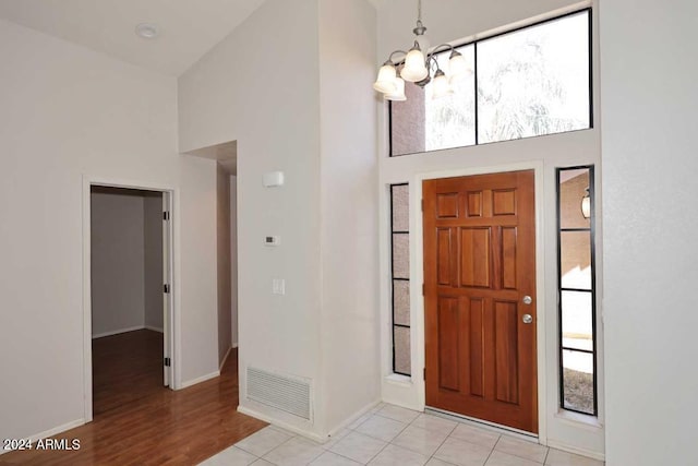 foyer featuring light hardwood / wood-style flooring, a healthy amount of sunlight, a high ceiling, and a notable chandelier