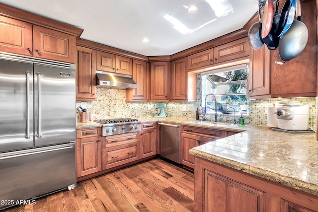 kitchen featuring sink, appliances with stainless steel finishes, light stone counters, tasteful backsplash, and light hardwood / wood-style floors