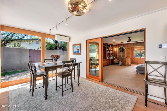 dining area with wooden walls, a wall mounted AC, carpet flooring, track lighting, and ornamental molding