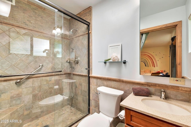 bathroom featuring toilet, tile walls, vanity, and a shower with shower door