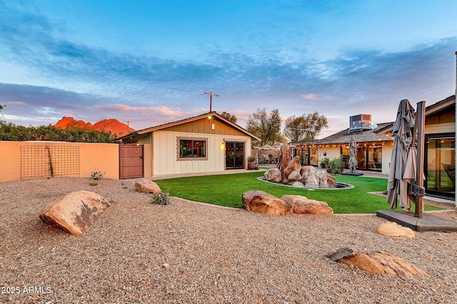 back house at dusk with a lawn