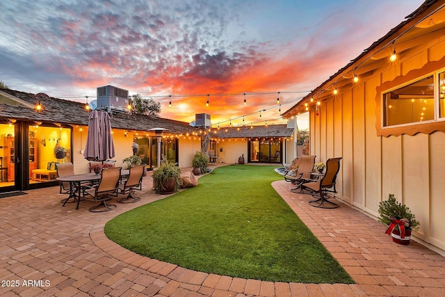 yard at dusk with central AC and a patio area