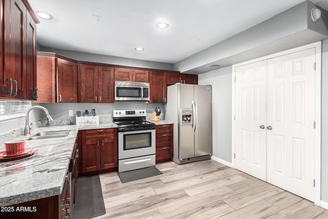 kitchen featuring light stone countertops, stainless steel appliances, light hardwood / wood-style floors, and sink