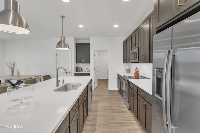 kitchen featuring light wood-style flooring, recessed lighting, light countertops, a sink, and stainless steel appliances