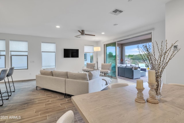 living room featuring a ceiling fan, visible vents, recessed lighting, wood finished floors, and baseboards