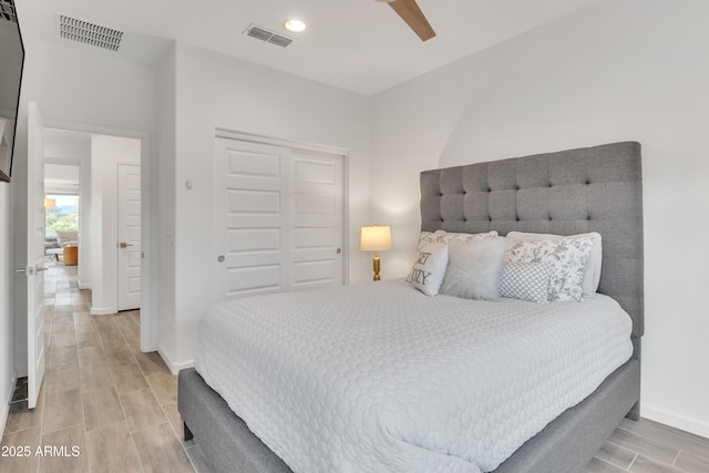 bedroom with visible vents, a closet, baseboards, and wood finish floors