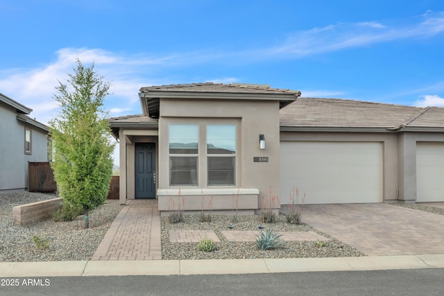 view of front of house featuring a garage, stucco siding, a tiled roof, and decorative driveway