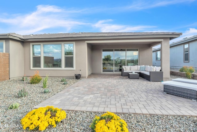 rear view of house with a patio, outdoor lounge area, and stucco siding
