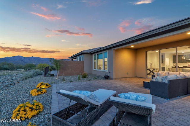 patio terrace at dusk featuring a mountain view, outdoor lounge area, and fence