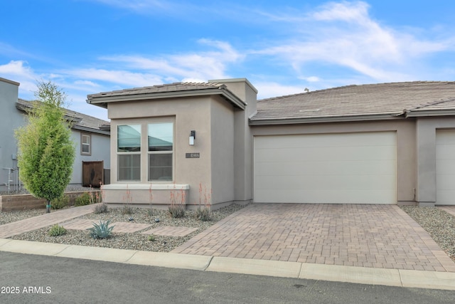 view of front of property with a garage, stucco siding, a tiled roof, and decorative driveway