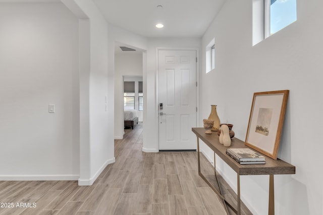 hall featuring light wood-type flooring, baseboards, visible vents, and recessed lighting