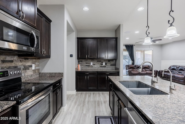 kitchen featuring appliances with stainless steel finishes, sink, tasteful backsplash, and decorative light fixtures