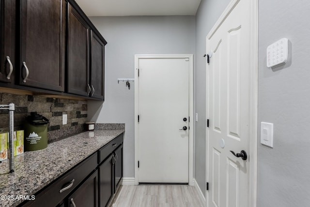 clothes washing area with light hardwood / wood-style flooring