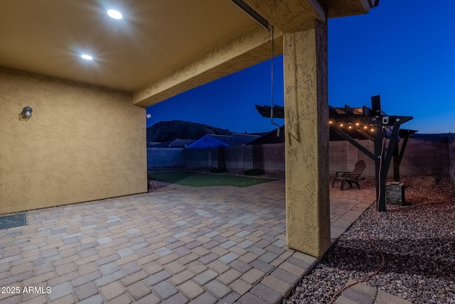 patio at night with a pergola and a mountain view