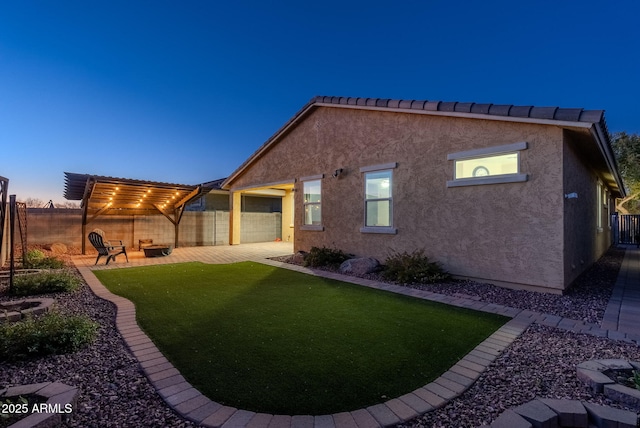 back house at dusk with a yard, a pergola, and a patio