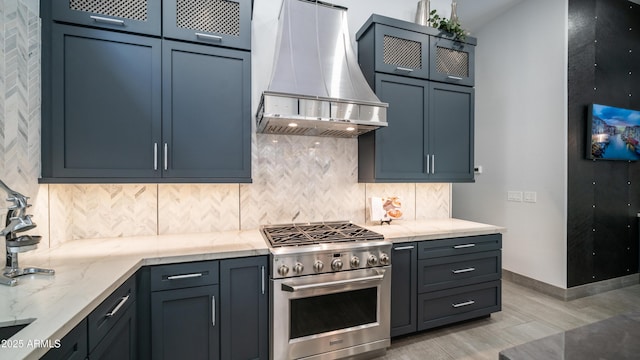 kitchen with tasteful backsplash, high end stainless steel range oven, wall chimney exhaust hood, and light stone countertops