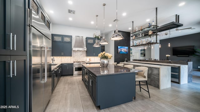 kitchen featuring a large island, tasteful backsplash, visible vents, custom range hood, and a kitchen breakfast bar