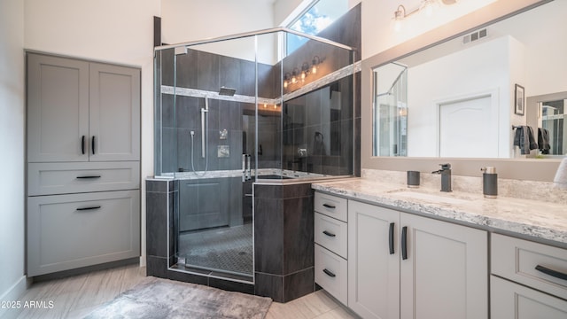 full bathroom featuring a stall shower, visible vents, and vanity