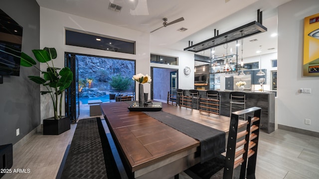 dining space with bar, visible vents, baseboards, and wood finished floors