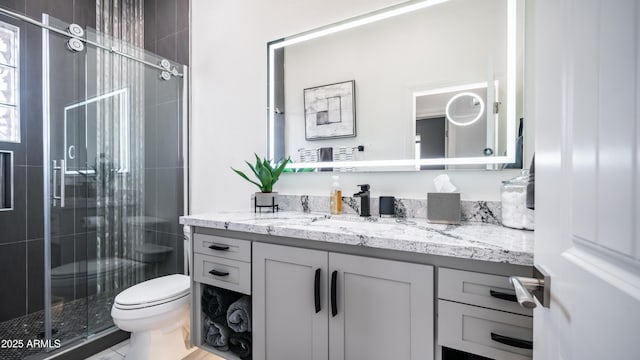 full bathroom featuring a stall shower, vanity, and toilet