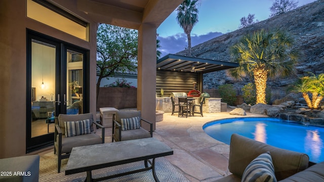 pool with an outdoor kitchen, fence, outdoor dry bar, and a patio