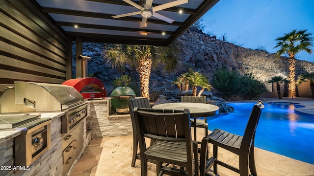 exterior space featuring outdoor dining area, grilling area, an outdoor kitchen, a mountain view, and an outdoor pool