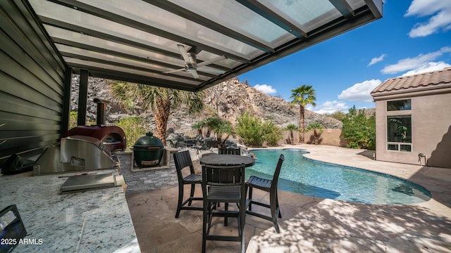 view of pool featuring area for grilling, an outdoor kitchen, a patio area, ceiling fan, and a fenced backyard